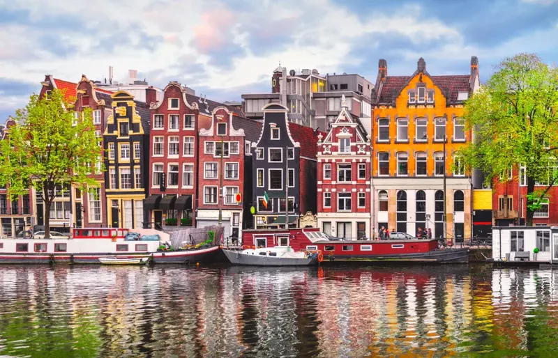 Colourful gabled canal houses and houseboats reflected in an Amsterdam canal