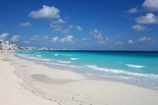 Turquoise Caribbean surf and white sand on Cancun beach with the Hotel Zone high-rises