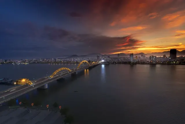 Dragon Bridge lit gold over the Han River at sunset with the Da Nang skyline