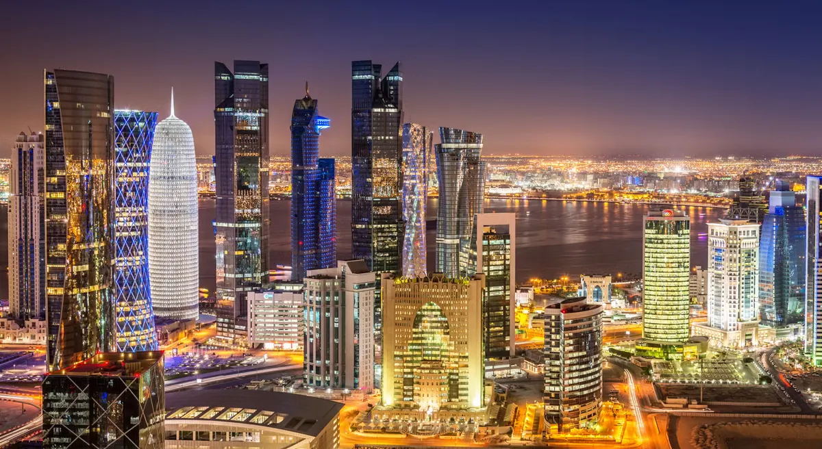 Doha's skyline towers lit up across the bay at night