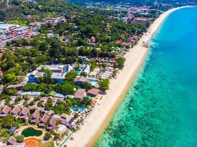 Aerial of a palm-fringed Koh Samui resort beach and clear turquoise shallows