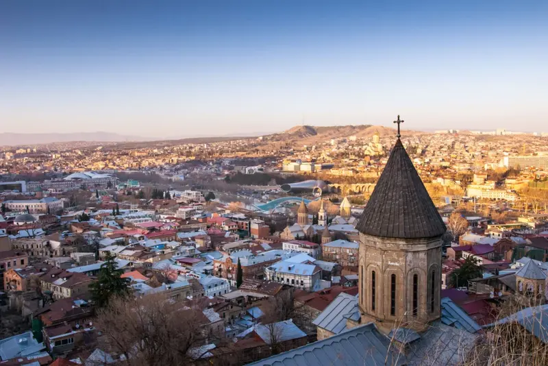 Tbilisi Old Town at golden hour with the Bridge of Peace over the Kura River