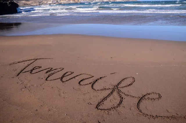 Tenerife written in the sand as waves roll in